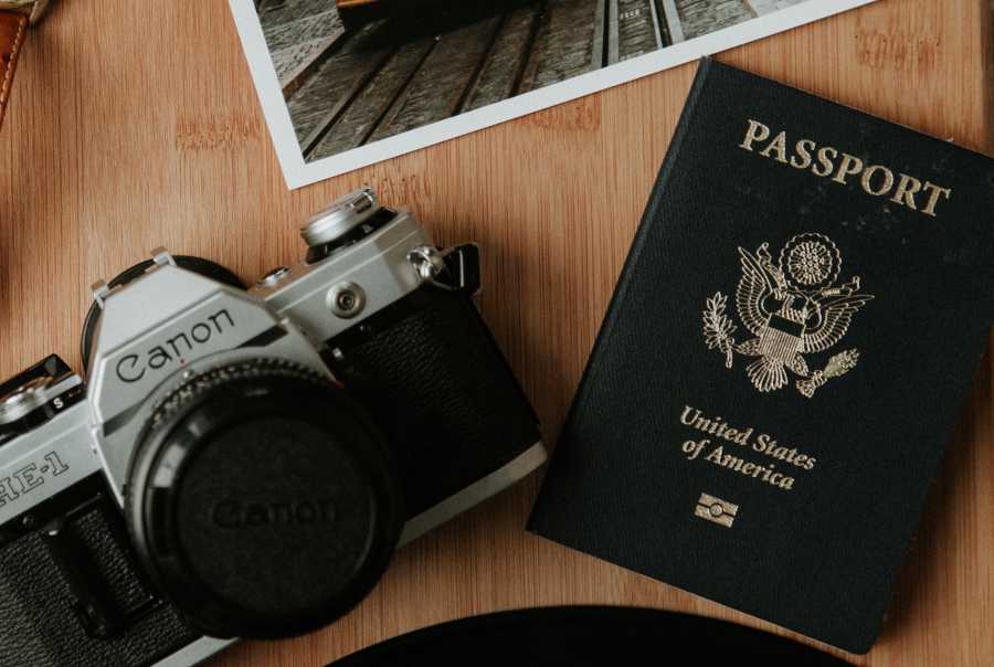 A camera and a passport sitting on a desk.